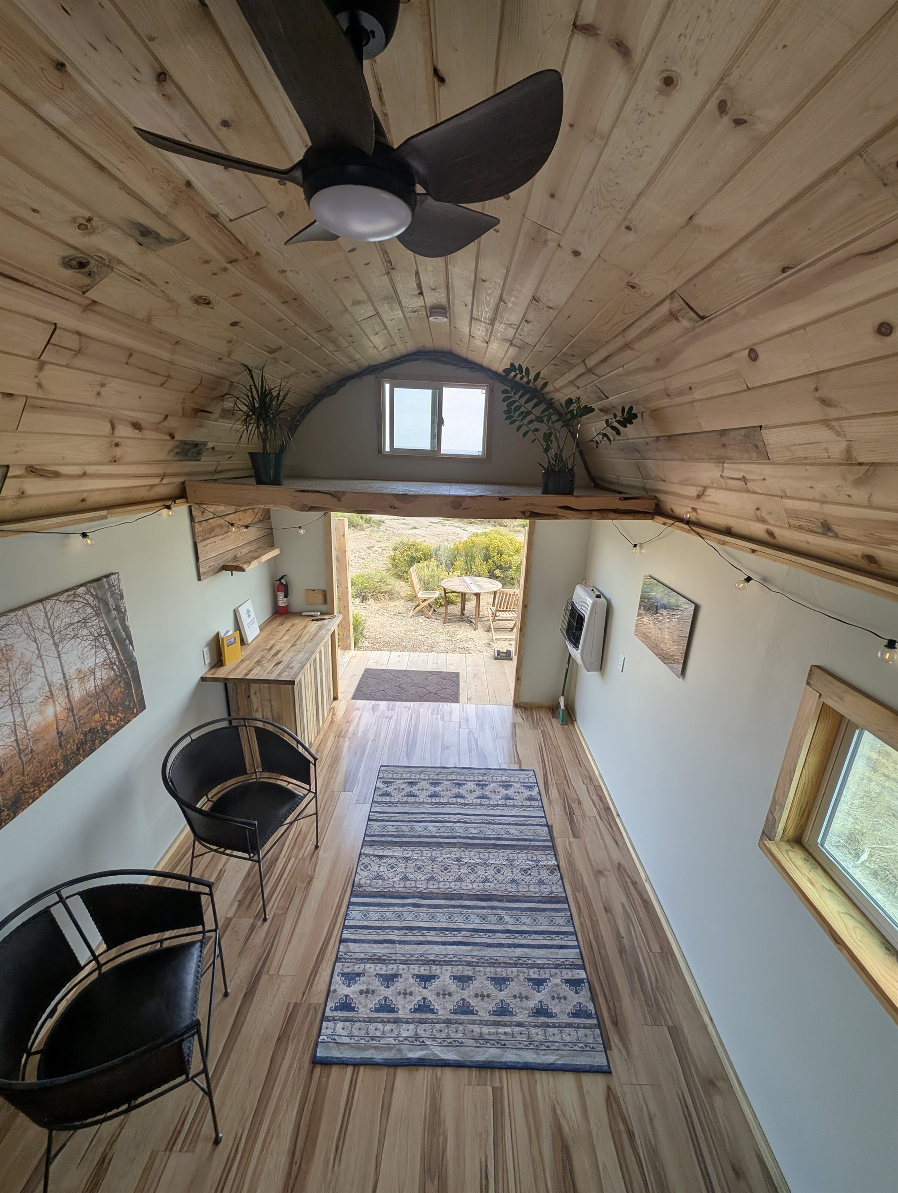 The cabin living space with wood floors, seating, and the door open to the desert